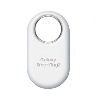 Samsung Galaxy SmartTag2 in White attached to a keyring, resting beside a Samsung Galaxy smartphone running SmartThings Find.