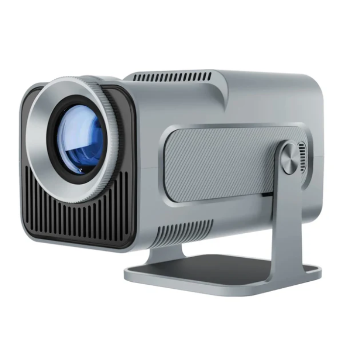 Magcubic HY320 grey projector on a coffee table projecting a 100‑inch movie scene onto a living room wall.